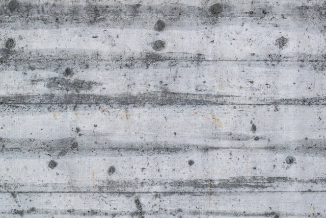 Worn concrete wall showing numerous holes and cracks