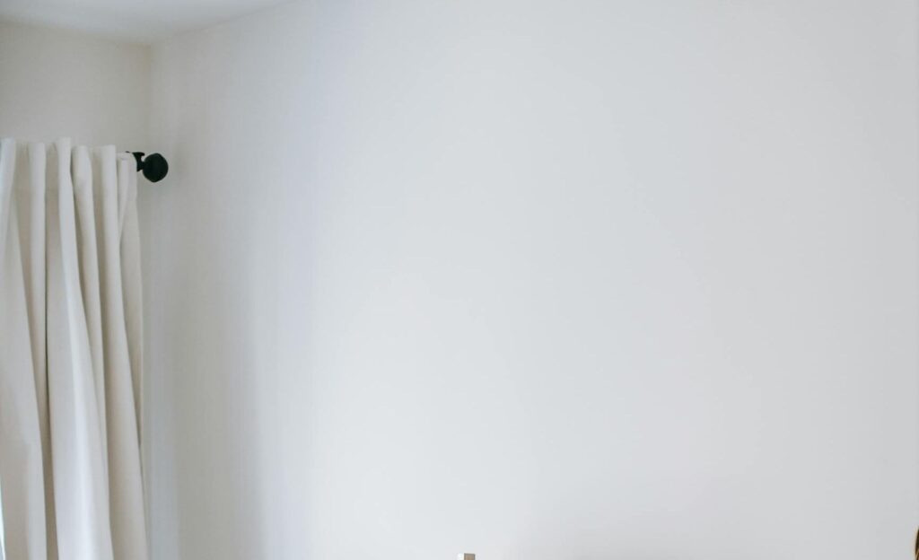 A serene white bed with a matching pillow and headboard